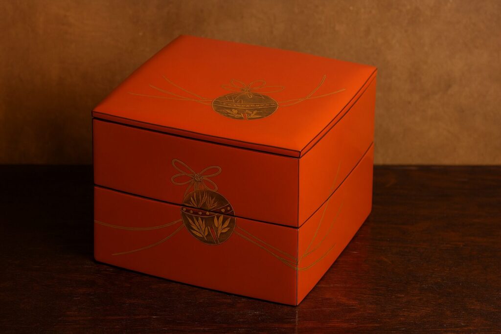 Vermilion Japanese lacquered jubako box with gold decorative motif and ribbon design